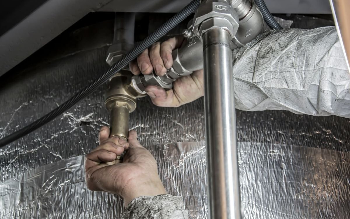 Licensed plumber repairing a pipe under a sink in a Charlotte home